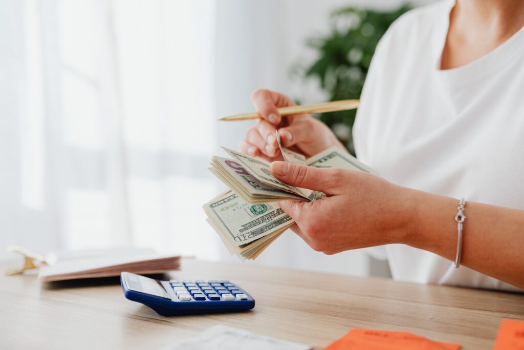 Person using calculator and pen to review monthly bills, key elements in upper frame, landscape finance photo with no text