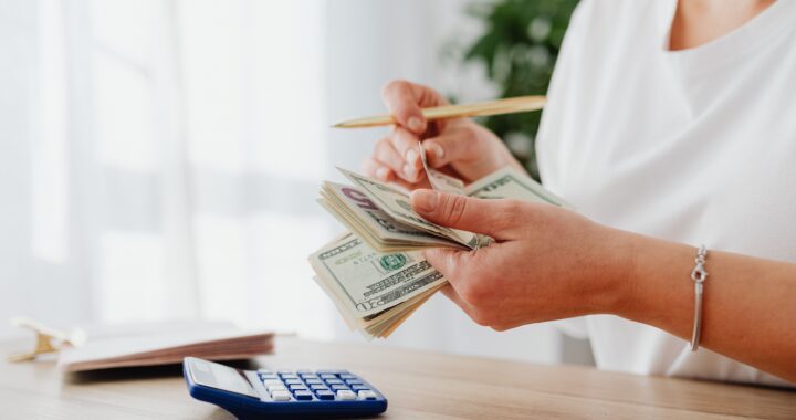 Person using calculator and pen to review monthly bills, key elements in upper frame, landscape finance photo with no text